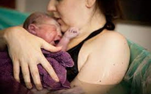 Mother holding her newborn baby in a calming water birth setting.