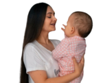A mother lovingly holds her baby in a moment of joyful connection.