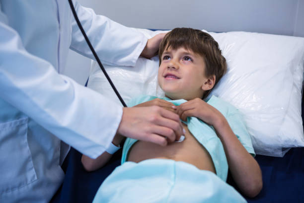 Doctor performing a pediatric laparoscopy on a young boy, with the child smiling while being examined.