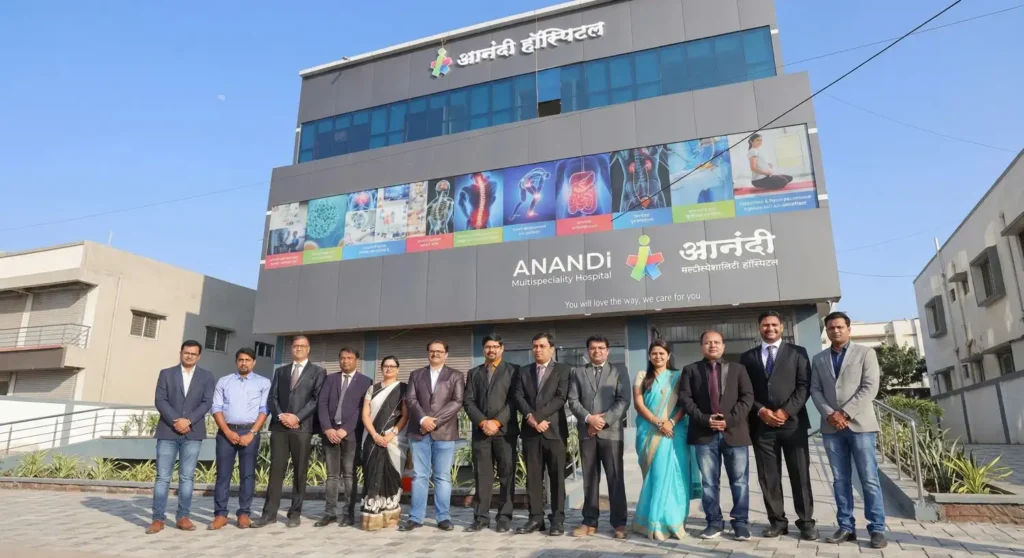 Group of medical staff standing in front of Anandi Multispeciality Hospital building exterior under clear sky.
